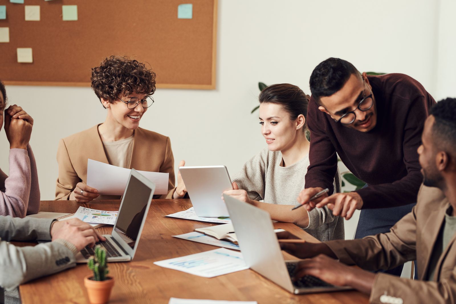 Equipo de trabajo reunido alrededor de una mesa con laptops