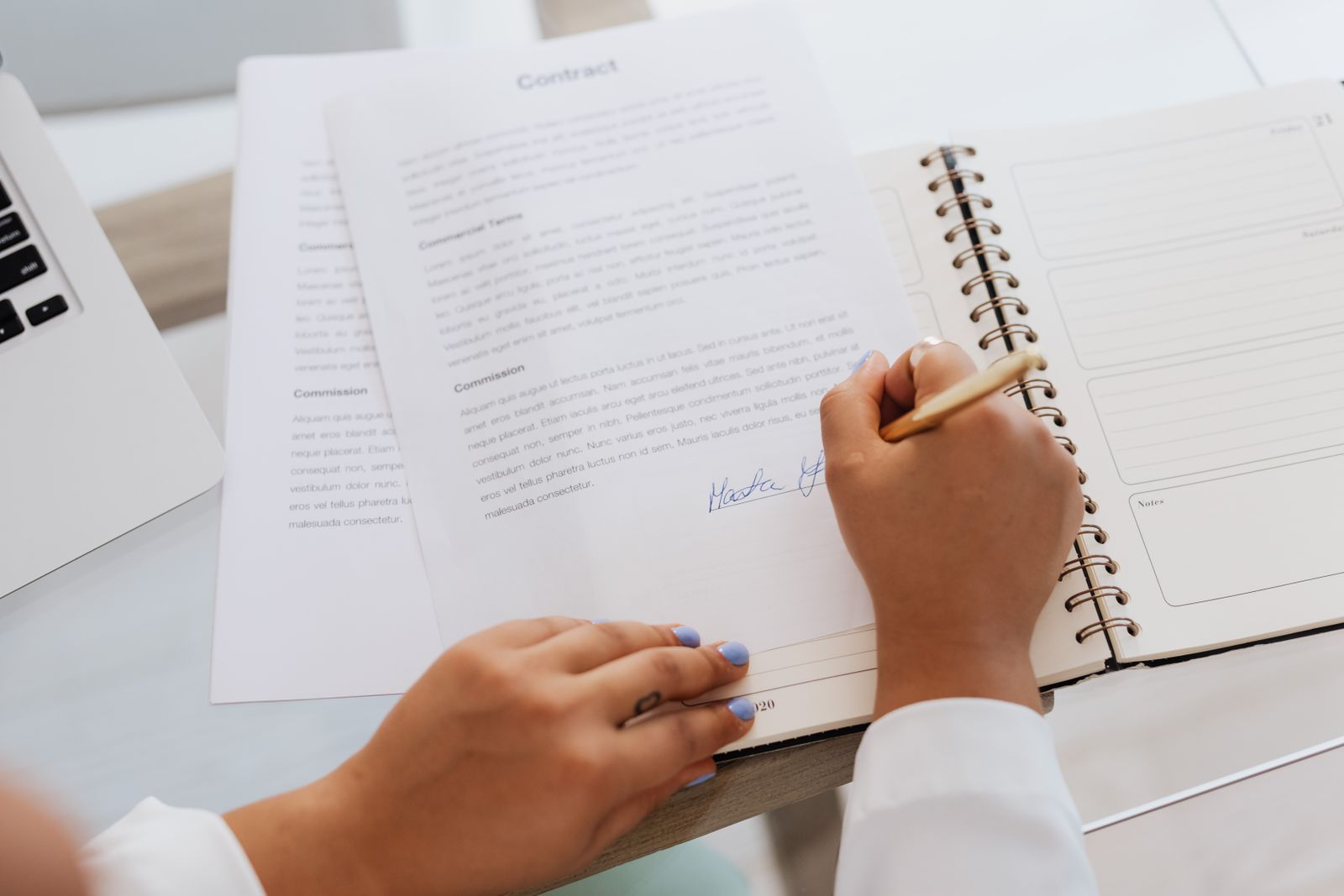 Manos firmando un contrato sobre un escritorio