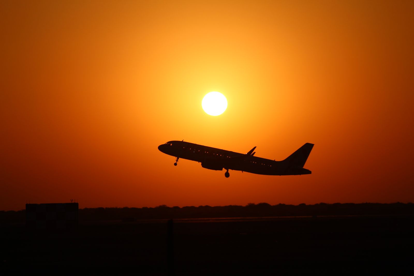 Silueta de un avión despegando al atardecer
